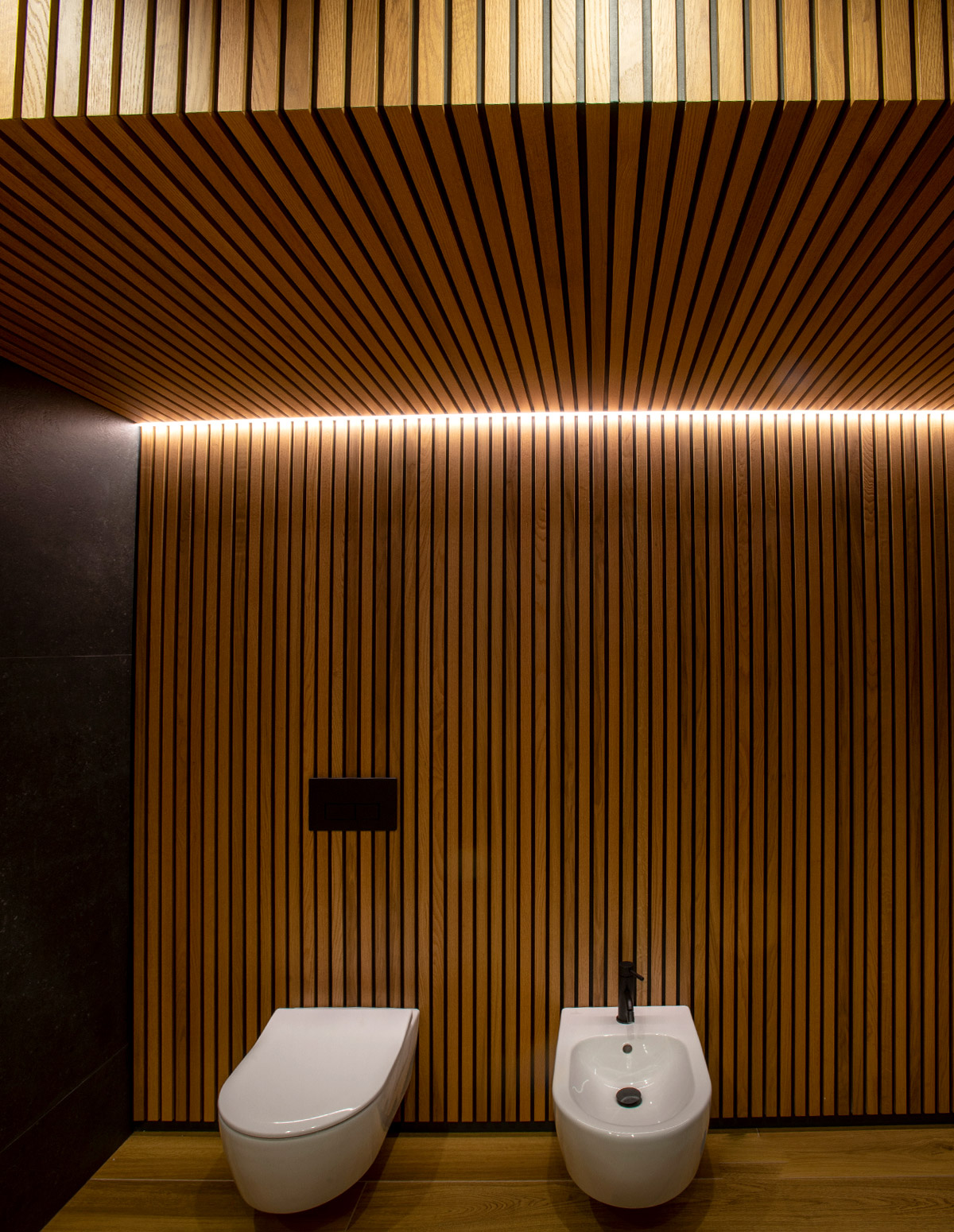 Baño con sanitarios sobre parede de madeira rastrelada, vista frontal